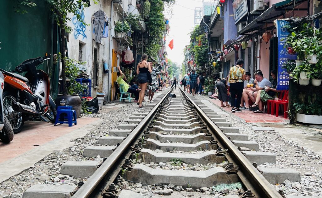 Hanoi market train station where people drink something and watch train passing 