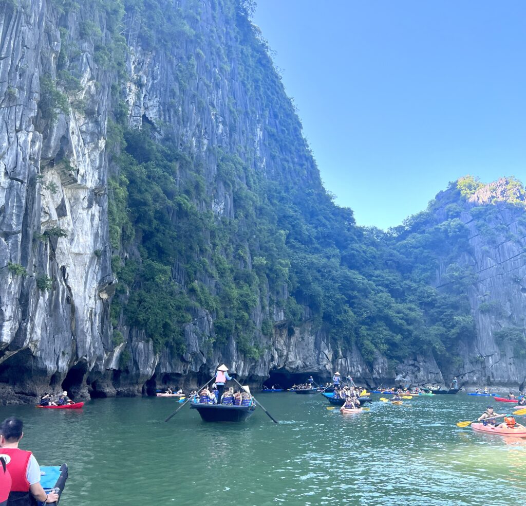 kayaking in Halong Bay with many other people in a beautiful sea