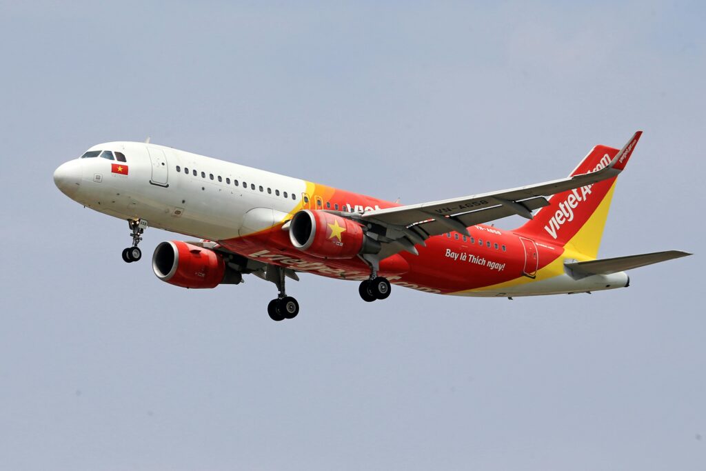 VietJet Air airplane flying with a clear sky background, showcasing vibrant branding.