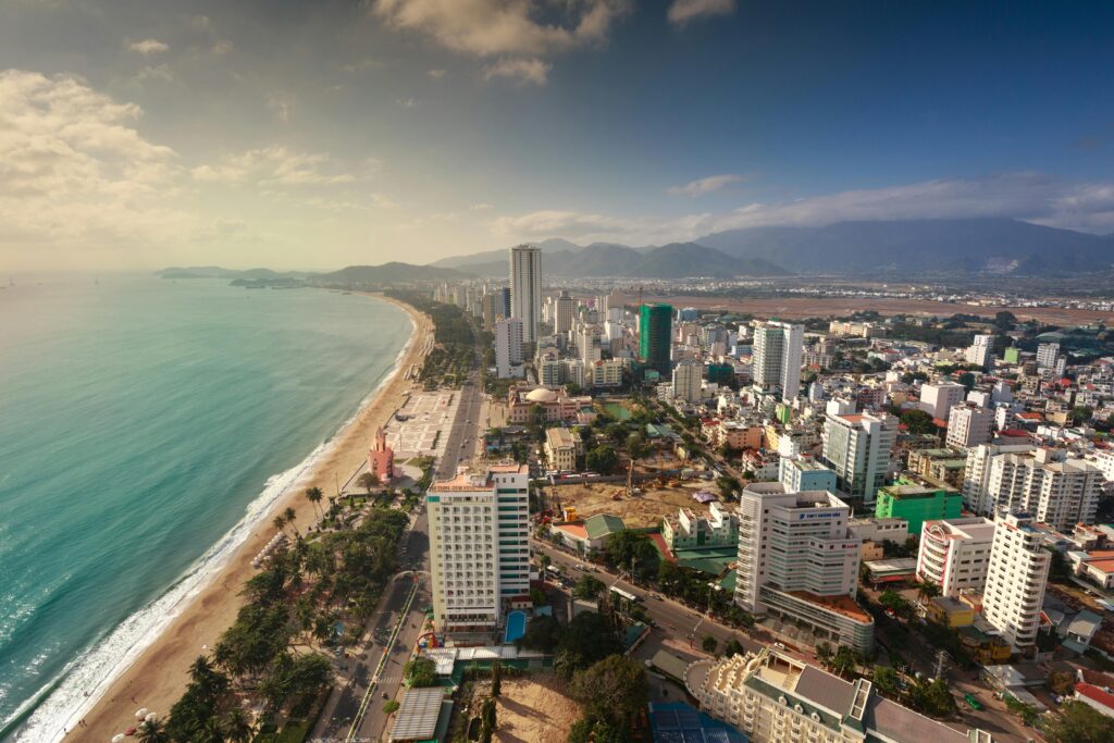 Aerial view of a coastal cityscape with beach and mountains.