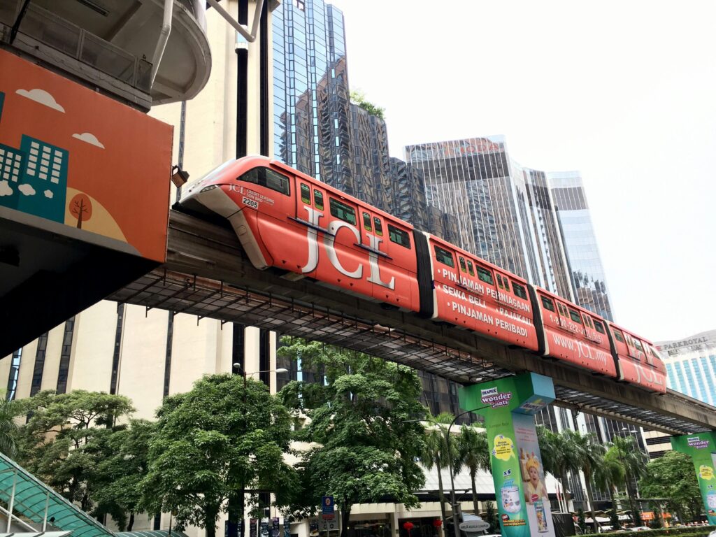 Urban monorail passing through Kuala Lumpur cityscape, showcasing modern architecture.